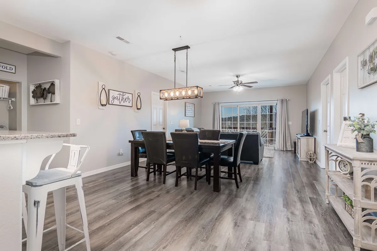 A warm dining area centered around a large table, adorned by a chandelier and framed by a window with elegant curtains. The setting radiates hospitality, ideal for family dinners, celebrations, or game nights.