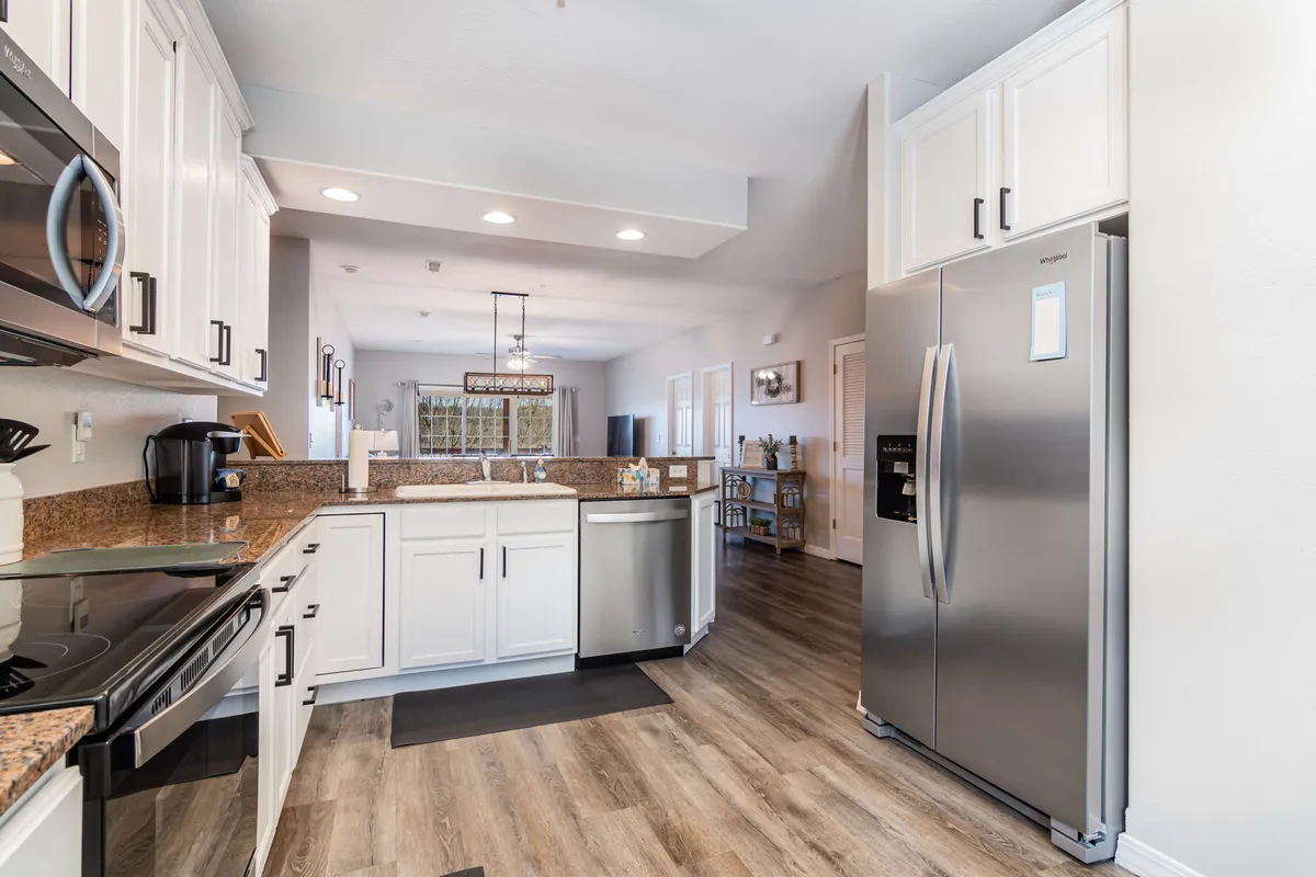 A bright, modern kitchen featuring a spacious kitchen island, stainless steel appliances, and granite countertops. The area is illuminated by a stylish light fixture, and the open layout invites both cooking and conversation.