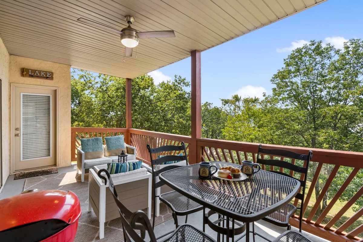 A private balcony set with a dining table, coffee mugs, pastries, comfortable seating cushions, and a grill. The area overlooks natural scenery, inviting guests to enjoy alfresco dining or unwind in the fresh air.
