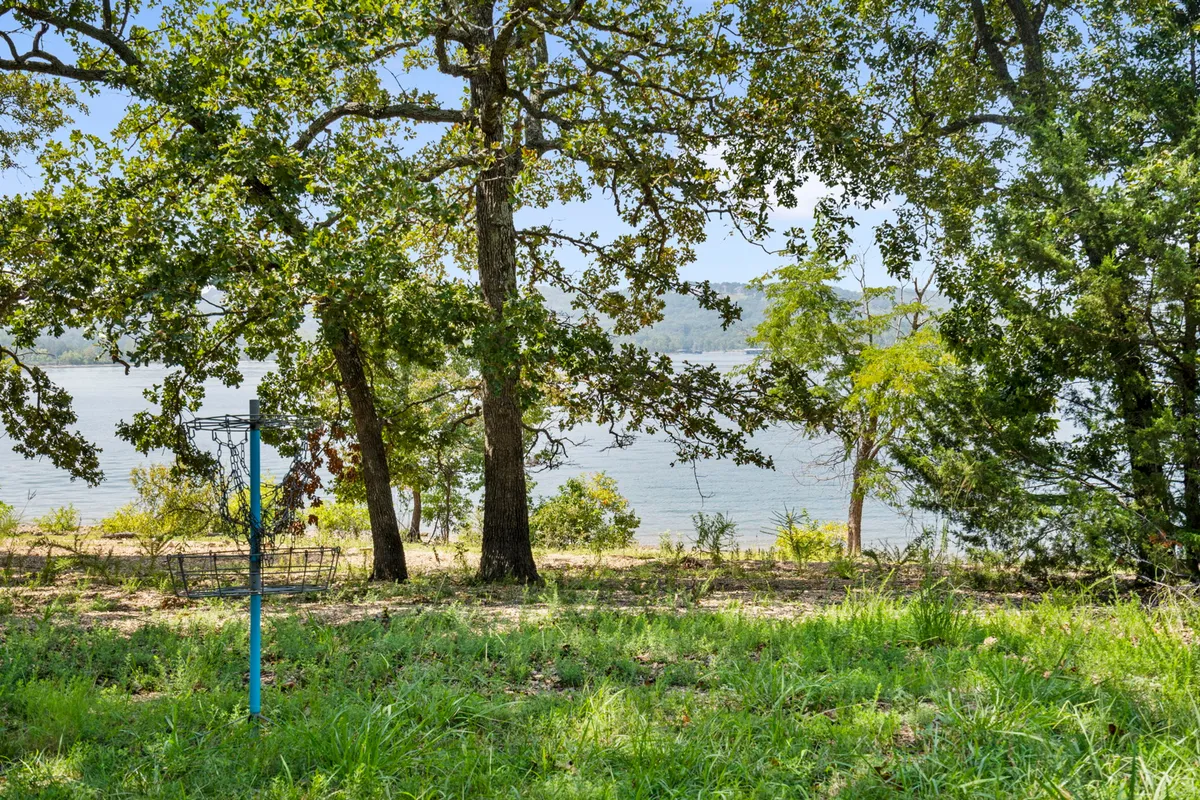 A peaceful lakeshore scene with grassy banks, mature trees, and the calm expanse of Table Rock Lake. The inviting landscape suggests opportunities for picnicking, fishing, or simply soaking in the tranquil environment, bringing to life the theme of lakeside leisure and exploration.