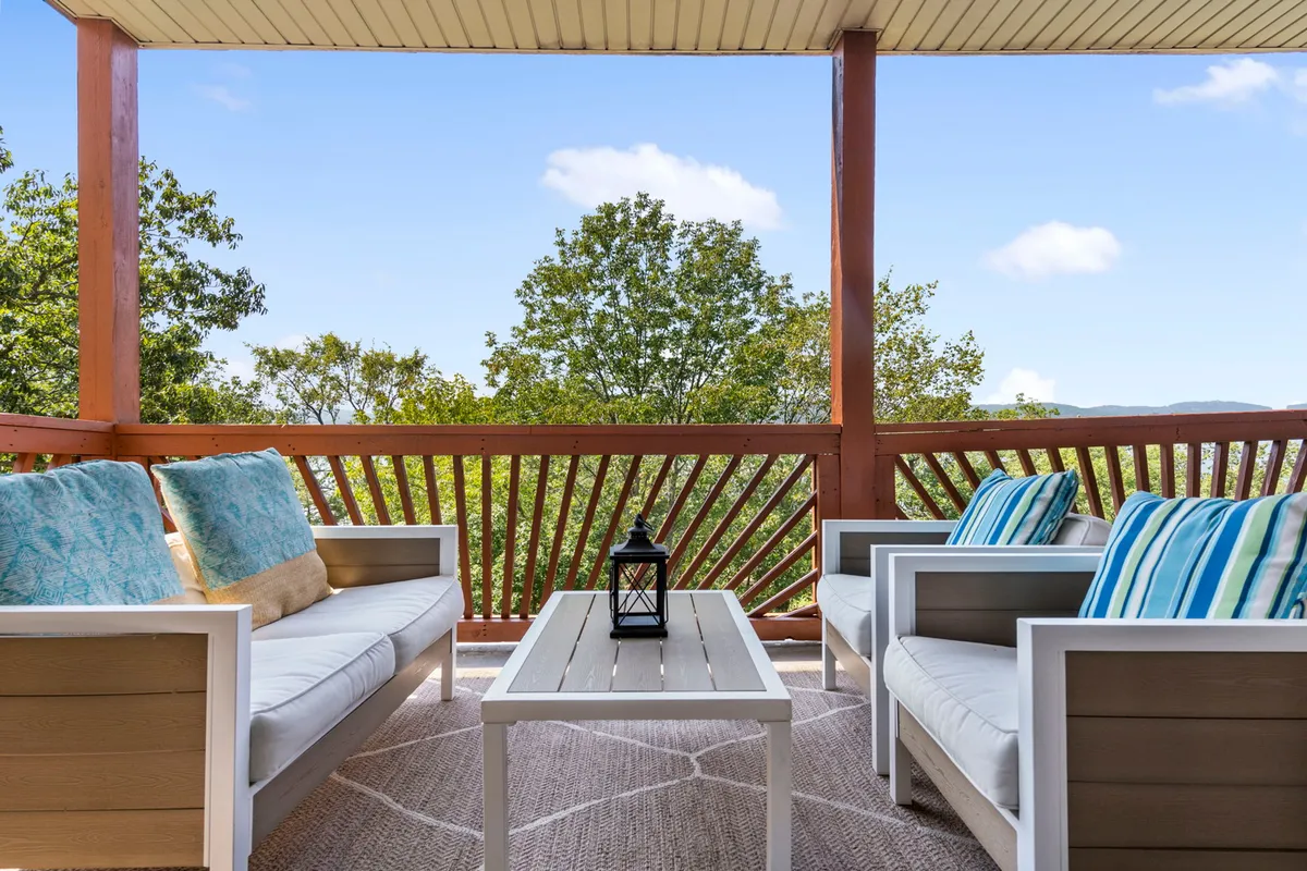 The hero image showcases a welcoming exterior seating area on the condo's lakeside balcony, featuring cozy chairs adorned with decorative cushions and a coffee table topped with a stylish lantern—all set against the serene backdrop of Table Rock Lake, perfect for relaxing or gathering with loved ones.